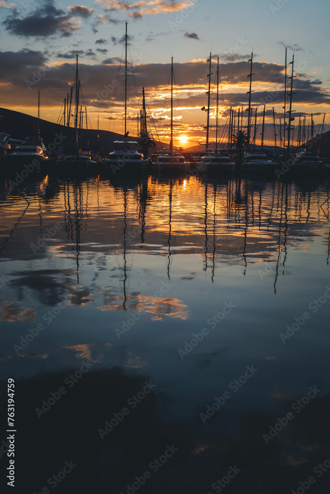 Boats, motorboats and yachts with masts in the port at sunset, beautiful seascape, marine travel and adventures