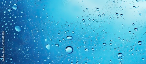 Bubbles of liquid float in the water, creating a mesmerizing display against the electric blue background. The moisture in the air forms droplets, resembling a drizzle of precipitation