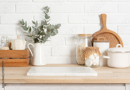 White stone podium on wooden kitchen counter with various rustic decor utensils and brick wall