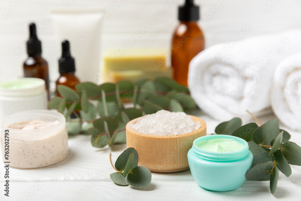 Beautiful spa composition on a wooden background with eucalyptus leaves. Beauty and fashion spa concept with body cream, scrub, mask, essential oil and sea salt.Cosmetic product. Copy space. Beautiful spa composition on a wooden background with eucalyptus leaves. Beauty and fashion spa concept with body cream, scrub, mask, essential oil and sea salt.Cosmetic product. Copy space.