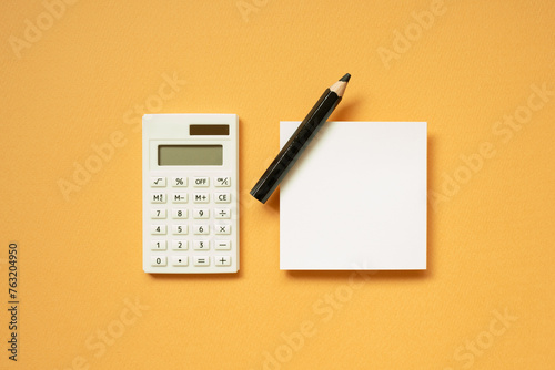 Obraz na płótnie Office supply. Calculator, notepad, pencil on orange desk background. flat lay, top view, copy space w salonie