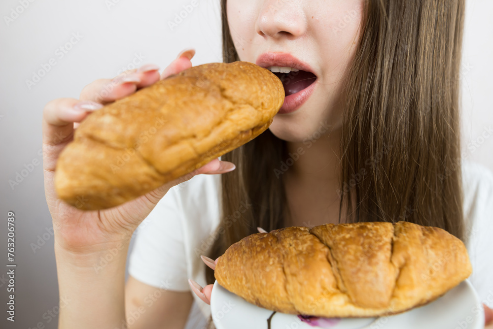 young beautiful girl eating a croissant, close-up, crop photo. female mouth eating croissant young beautiful girl eating a croissant, close-up, crop photo. female mouth eating croissant