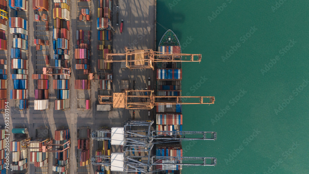 Obraz premium Aerial top view over international containers cargo ship at industrial import-export port prepare to load containers with big container loader ship vessel. global transportation and logistic business.
