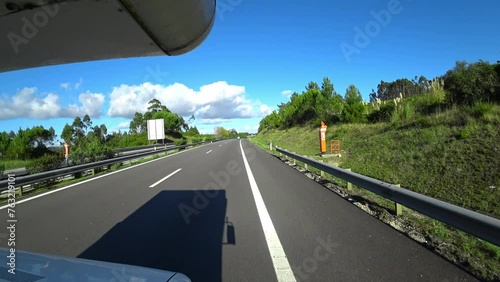 Big Camper Riding On The Road Across Green Trees