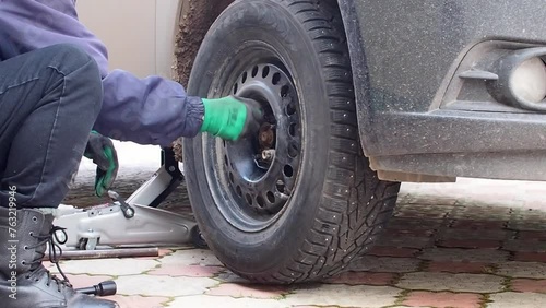 Kandra, Bashkortostan, Russia - December 01, 2023: Car mechanic removing car wheel covers using drill tool in service garage. photo