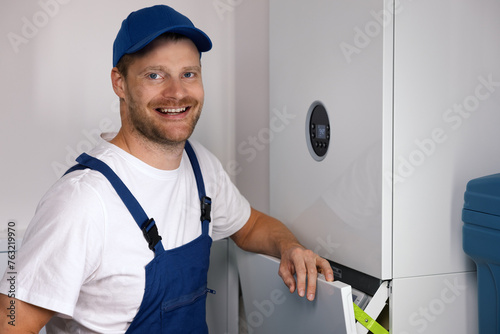 smiling maintenance and repair service worker working with house gas heating boiler