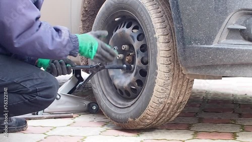 Kandra, Bashkortostan, Russia - December 01, 2023: Car mechanic removing car wheel covers using drill tool in service garage. photo