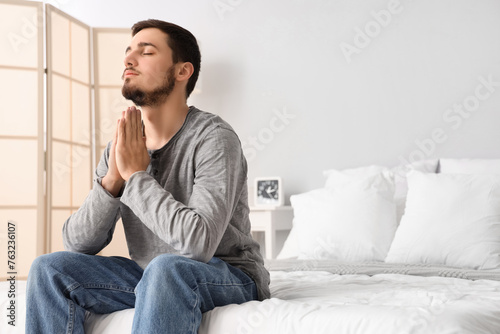 Young man meditating in bed...