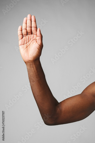 A mans arm is raised high in the air, hand held up with fingers spread apart