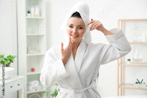 Beautiful woman with under-eye patches after shower in bathroom
