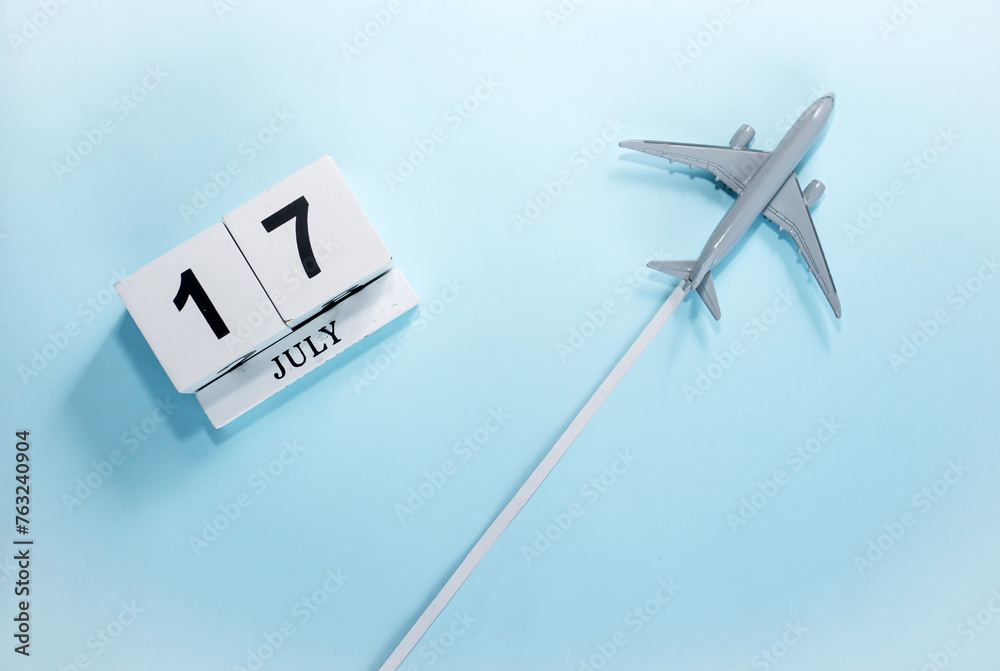July calendar with number 17. Top view of a calendar with a flying passenger plane. Scheduler. Travel concept. Copy space. July calendar with number 17. Top view of a calendar with a flying passenger plane. Scheduler. Travel concept. Copy space.