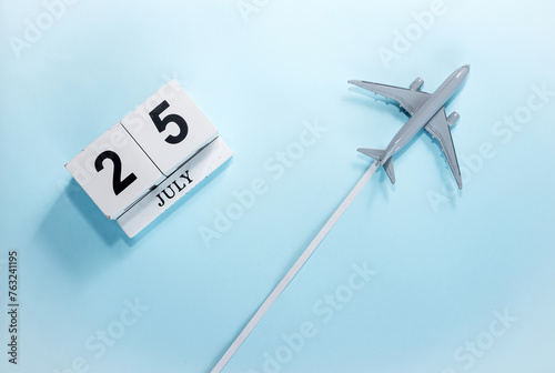 July calendar with number  25. Top view of a calendar with a flying passenger plane. Scheduler. Travel concept. Copy space. photo