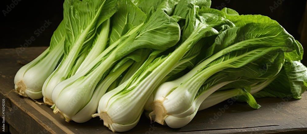 A pile of fresh green cabbage, a staple food in many cuisines, is displayed on a wooden table. This versatile vegetable is a popular ingredient in various dishes A pile of fresh green cabbage, a staple food in many cuisines, is displayed on a wooden table. This versatile vegetable is a popular ingredient in various dishes