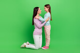 Full length photo of shiny cheerful little girl mom dressed casual clothes cuddling isolated green color background