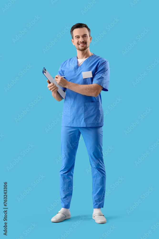 Portrait of male dentist with clipboard on blue background Portrait of male dentist with clipboard on blue background