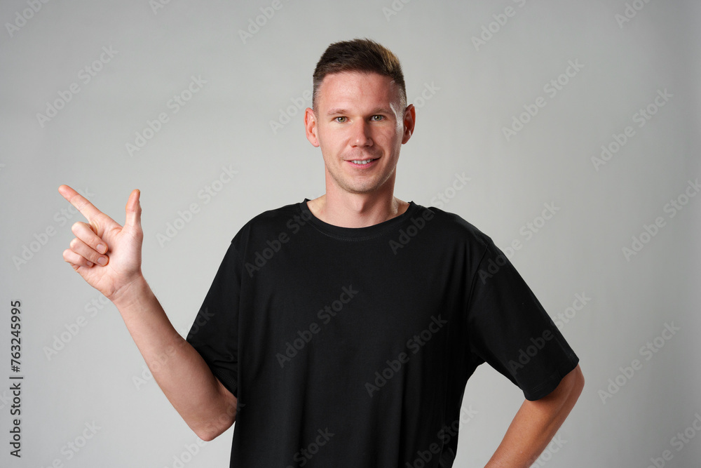 Young man pointing to the side to present a product on gray background Young man pointing to the side to present a product on gray background