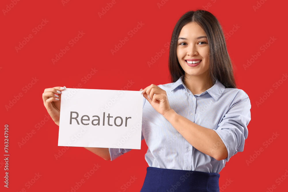 Young Asian woman holding paper with word REALTOR on red background Young Asian woman holding paper with word REALTOR on red background