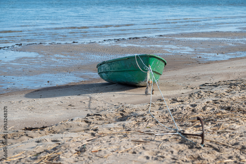 Fishing boat on a sandy beach with a rope and anchor in the foreground, selective focus
