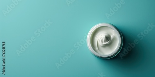 A pot of moisturizer against a calming teal background, suitable for skincare product branding or as an example in a beauty blog post