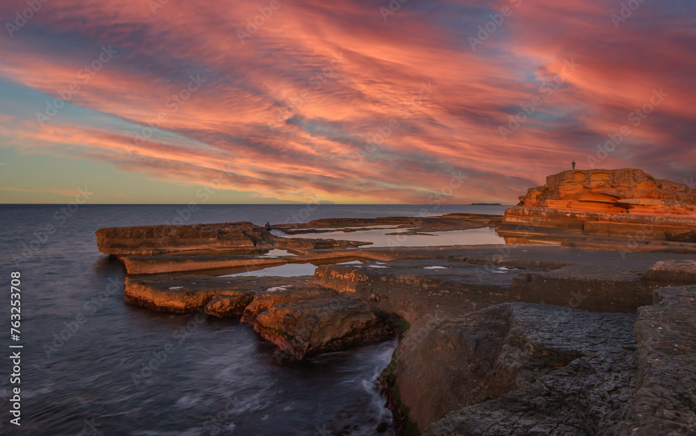 sunset light and unique shaped cliffs by the sea colorful clouds in the sky sunset light and unique shaped cliffs by the sea colorful clouds in the sky