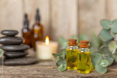 Eucalyptus essential oil in a glass bottle with green eucalyptus leaves on a textured wooden background. Aromatherapy concept. Spa. Natural organic ingredients for cosmetics and body care.Copy space