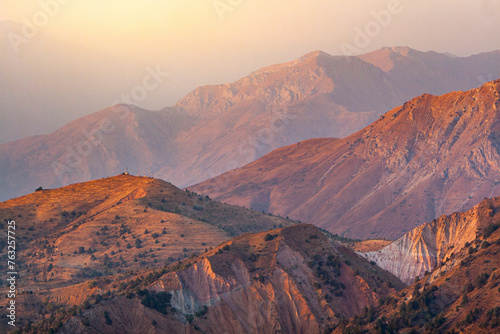 Aerial view of scenic Uzbekistan, illuminated in golden hour with beautiful mountain peaks and valleys, perfect for adventure and exploration. photo