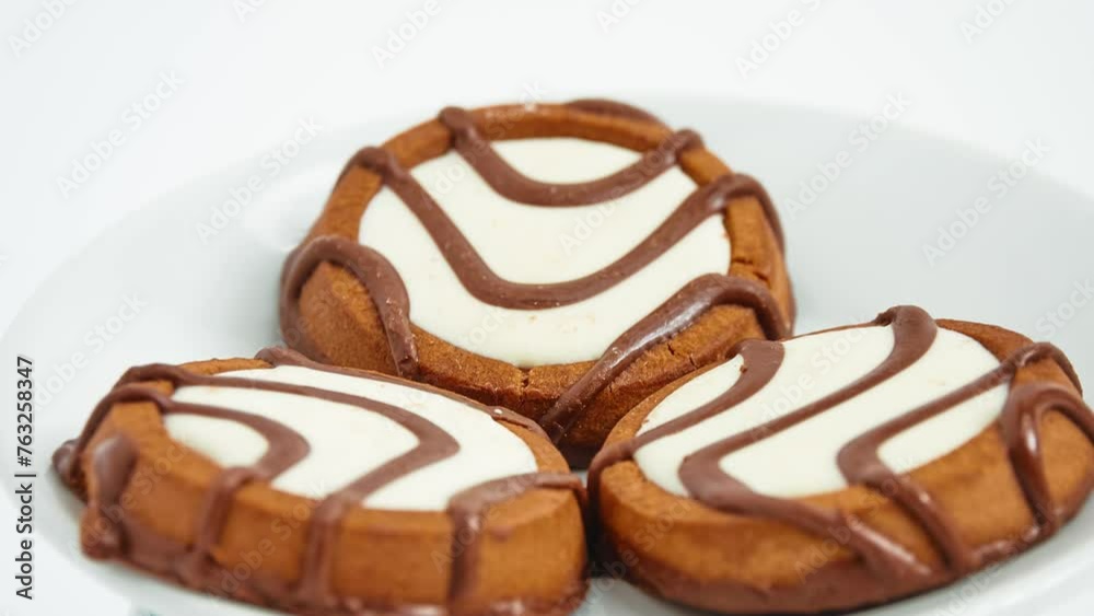 Gyration Round cookies with chocolate stripes and a white filling in plate on white background. Gyration Round cookies with chocolate stripes and a white filling in plate on white background.