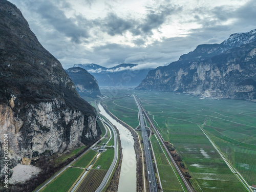 Aerial view of Adige River, vineyards, and village nestled among the lush green countryside, Salorno, South Tyrol, Italy. photo