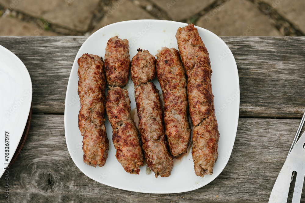 plate of grilled sausages on wooden background. Top view. Barbecue sausages presented on the fire. plate of grilled sausages on wooden background. Top view. Barbecue sausages presented on the fire.
