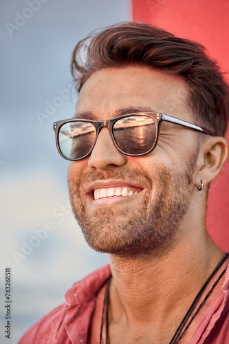 Foto Vertical portrait of an attractive adult man smiling as the evening sun reflects on his sunglasses