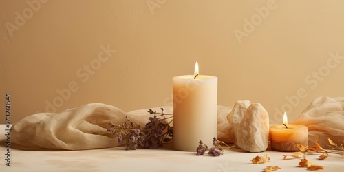 Burning candle on beige background. Warm aesthetic composition with stones and dry flowers. Home comfort, spa, relax and wellness concept