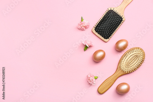 Hair brushes with flowers and Easter eggs on pink background photo