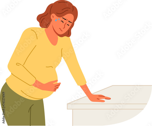 Pregnant woman holds stomach, standing near cabinet, experiencing pain due to complications caused by fetal development disorders. Pregnant girl needs hospitalization to avoid miscarriage