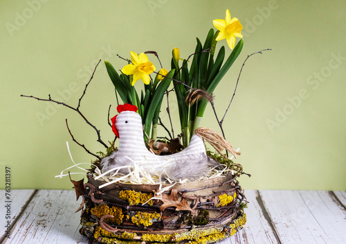 Easter decor in rustic style.Nest, chicken, yellow daffodils on light green background.Handmade.Concept of home comfort and decor on  bright holiday of Easter. Copy space.