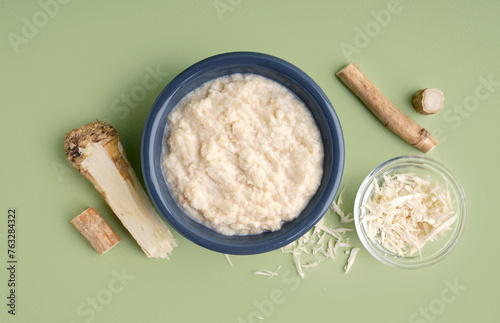 Foto Horseradish sauce in bowls with ground horseradish root on green background