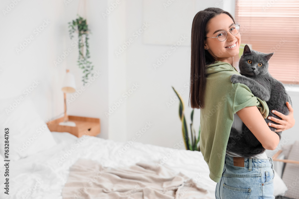 Young woman with cute British Shorthair cat in bedroom Young woman with cute British Shorthair cat in bedroom