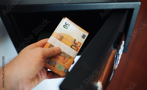 Man puts or takes euro banknotes from a safe.