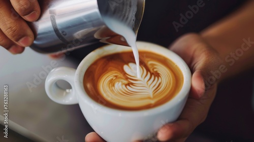 Hands of a person pouring steamed milk into a cup of espresso, creating a beautiful swirl