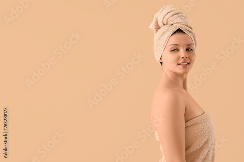 Young woman in towels after shower on beige background