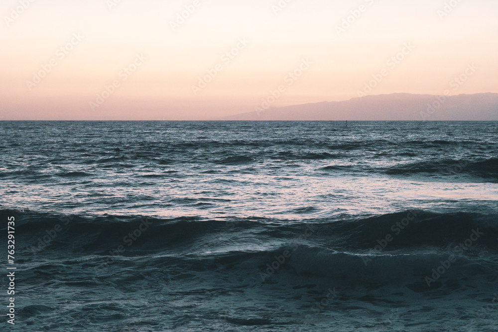 Playa al atardecer con olas rompiendo en las rocas