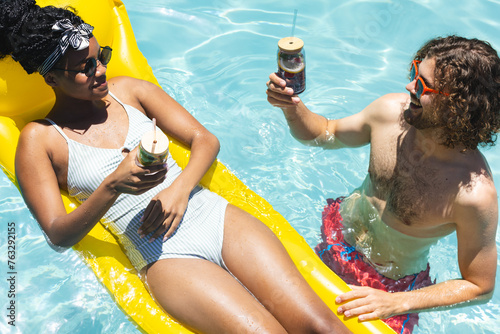 A diverse couple enjoys drinks in pool