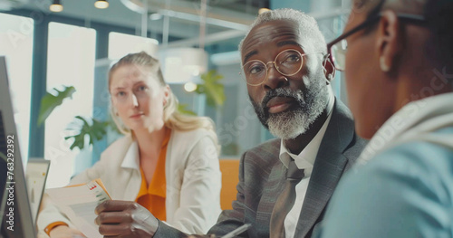 Group of diverse people sitting around a computer screen