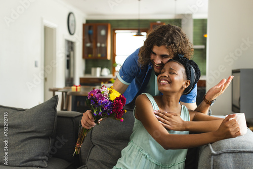 A diverse couple shares a tender moment at home on the couch