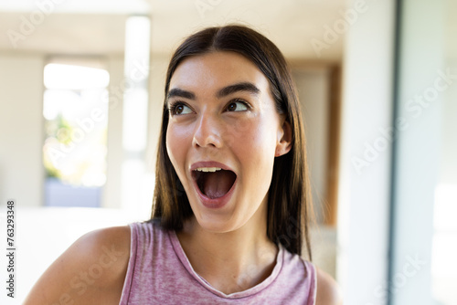 A young Caucasian brunette woman expresses excitement at home