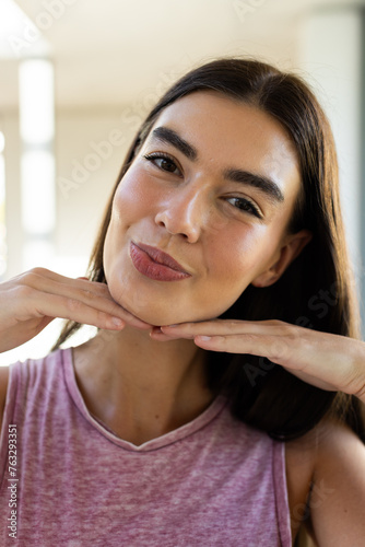 A young Caucasian brunette woman poses with a playful expression at home