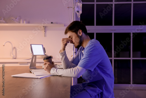 Tired male nurse with coffe...