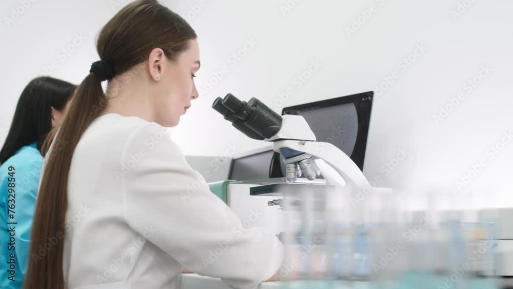 Scientist in a modern medical laboratory looking into a microscope. Microbiologist works on molecular samples in a modern laboratory with technological equipment. Scientist in a modern medical laboratory looking into a microscope. Microbiologist works on molecular samples in a modern laboratory with technological equipment.