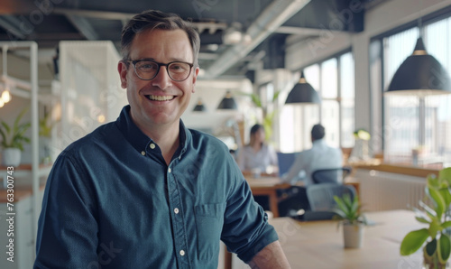 Smiling happy professional man standing in a modern workspace with arms crossed