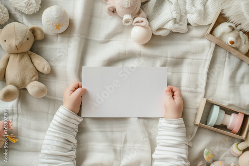 Top view of baby hands hold white blank card, near cute baby toys. Generative AI