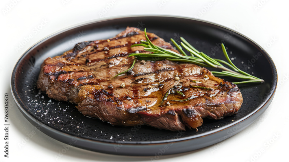 There is steak on a black plate, wooden table, white background